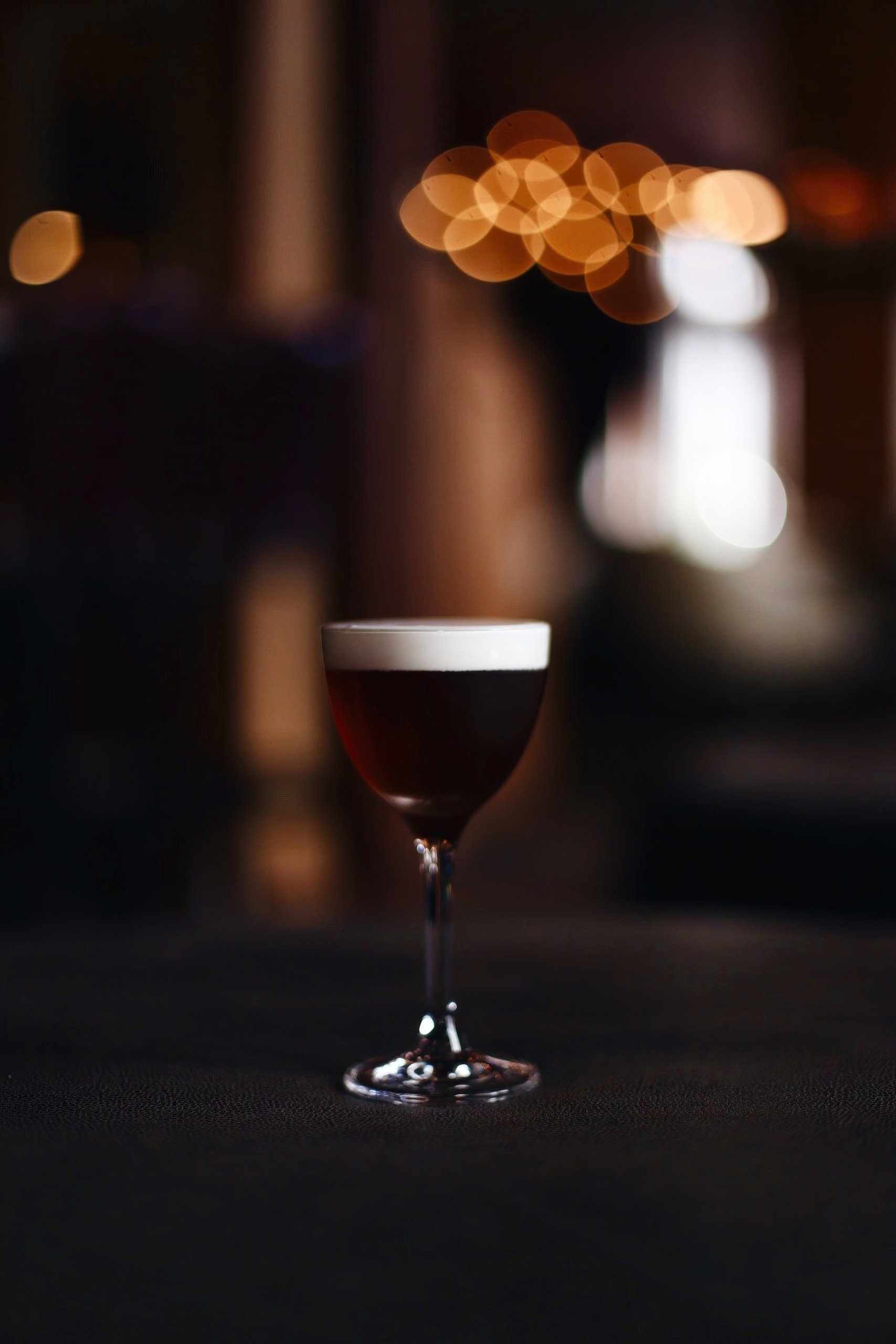 Dark brown drink in a clear glass on a table.
