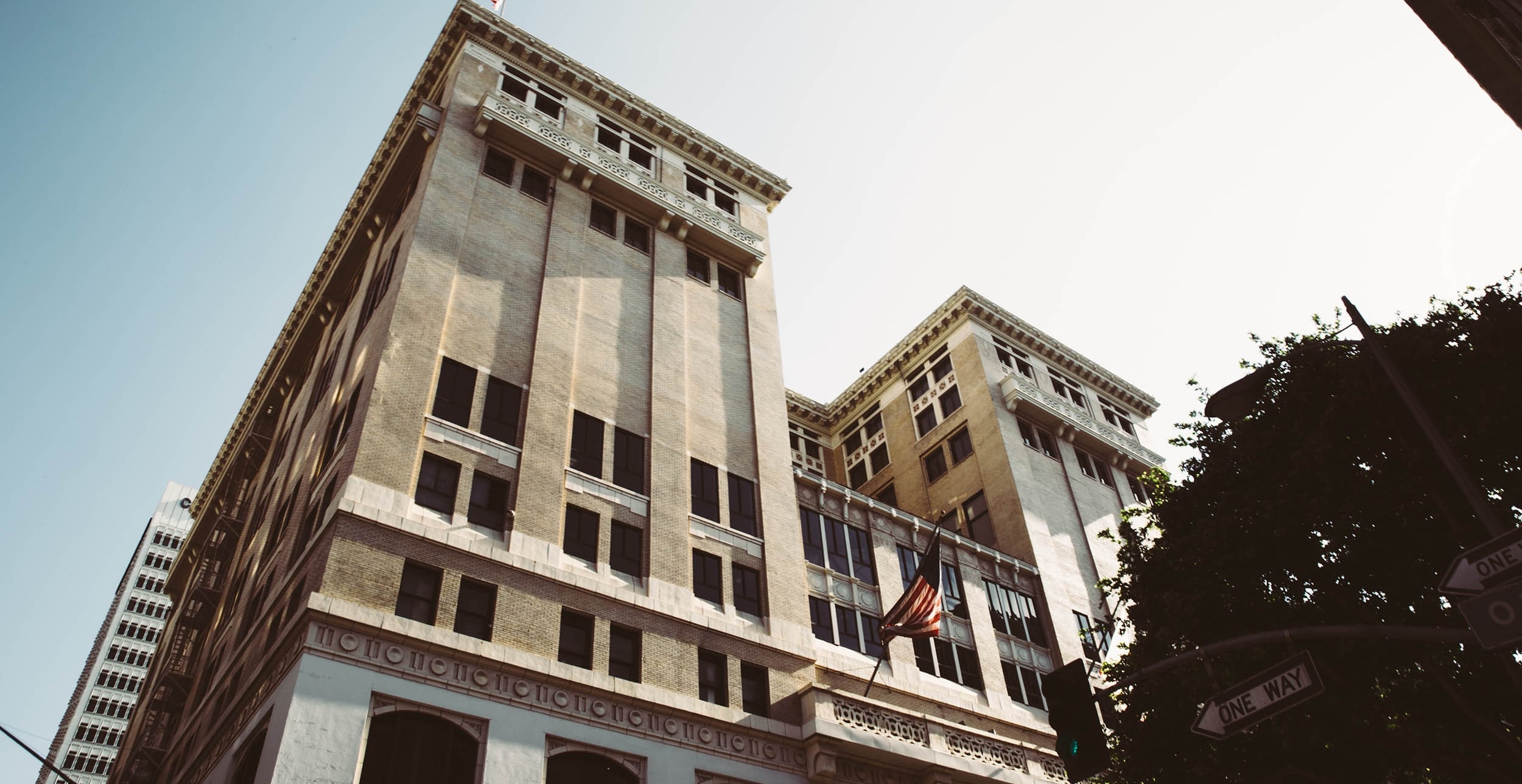A low-angle shot of a large, multi-story building with an American flag hanging from it.