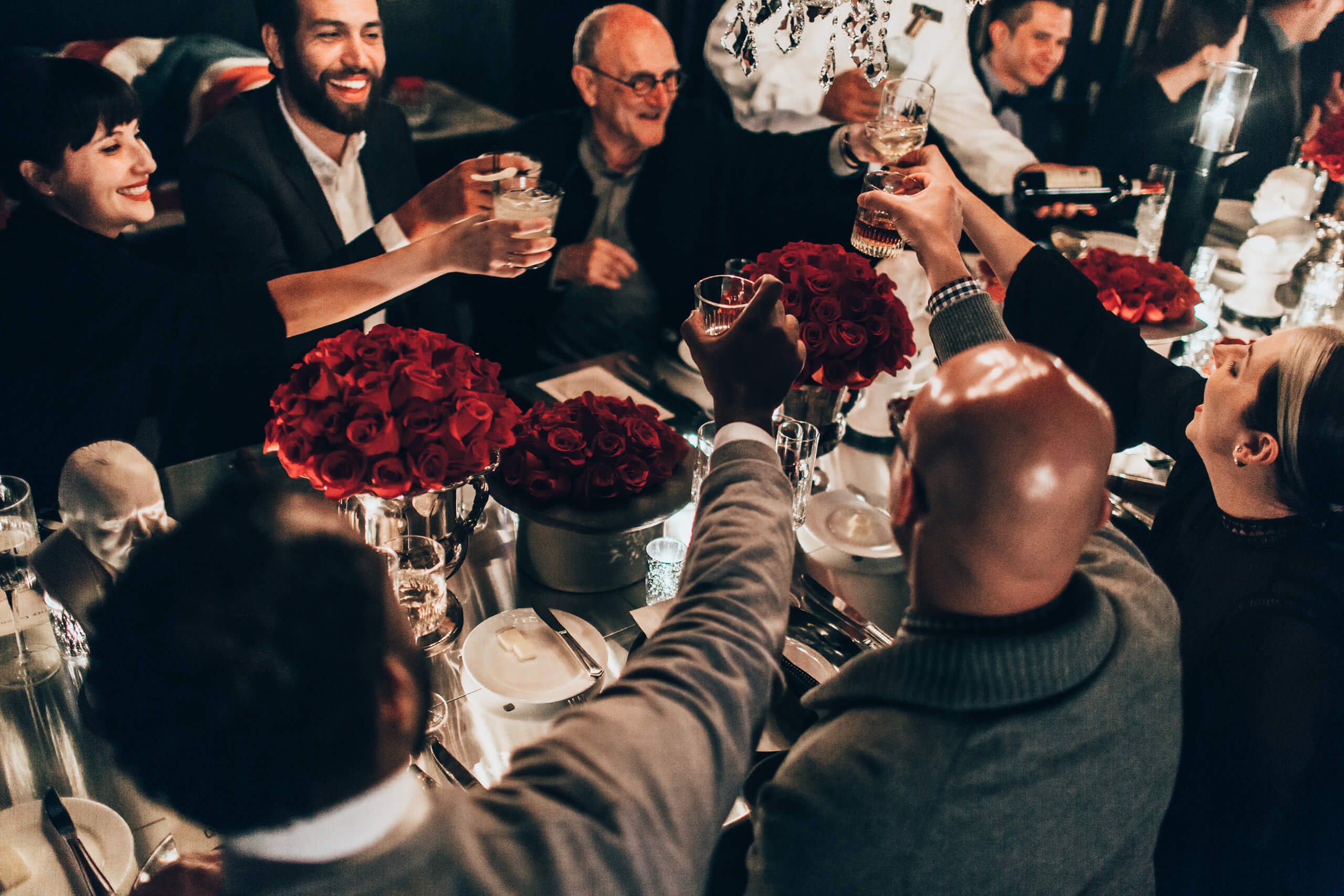 A group of friends raising their glasses in a toast at a beautifully set dinner table