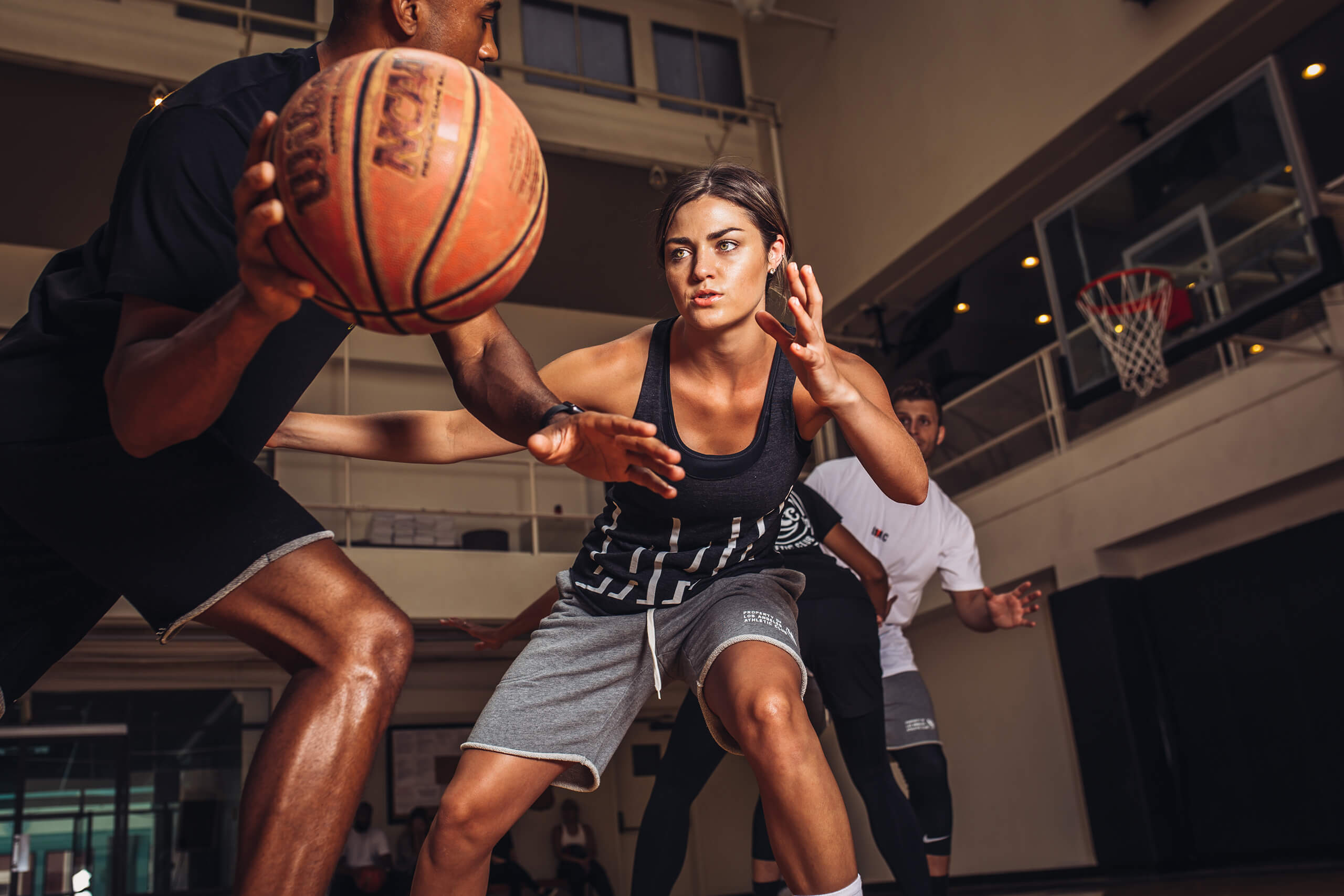 Man and woman enjoying a game of basketball in an indoor gym setting.