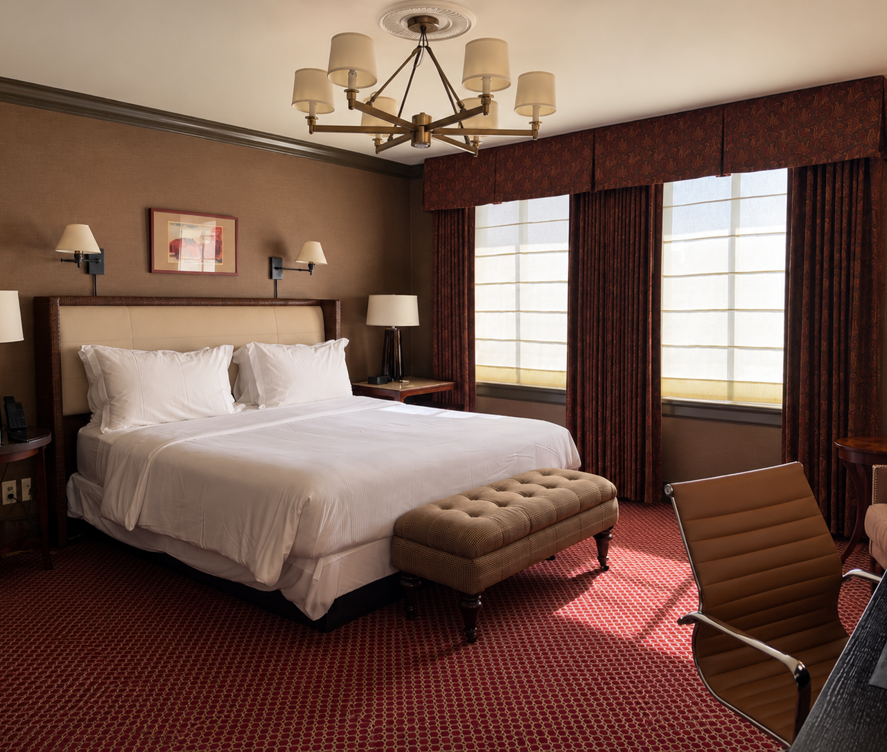 A hotel room with a large bed, a chair, and a window