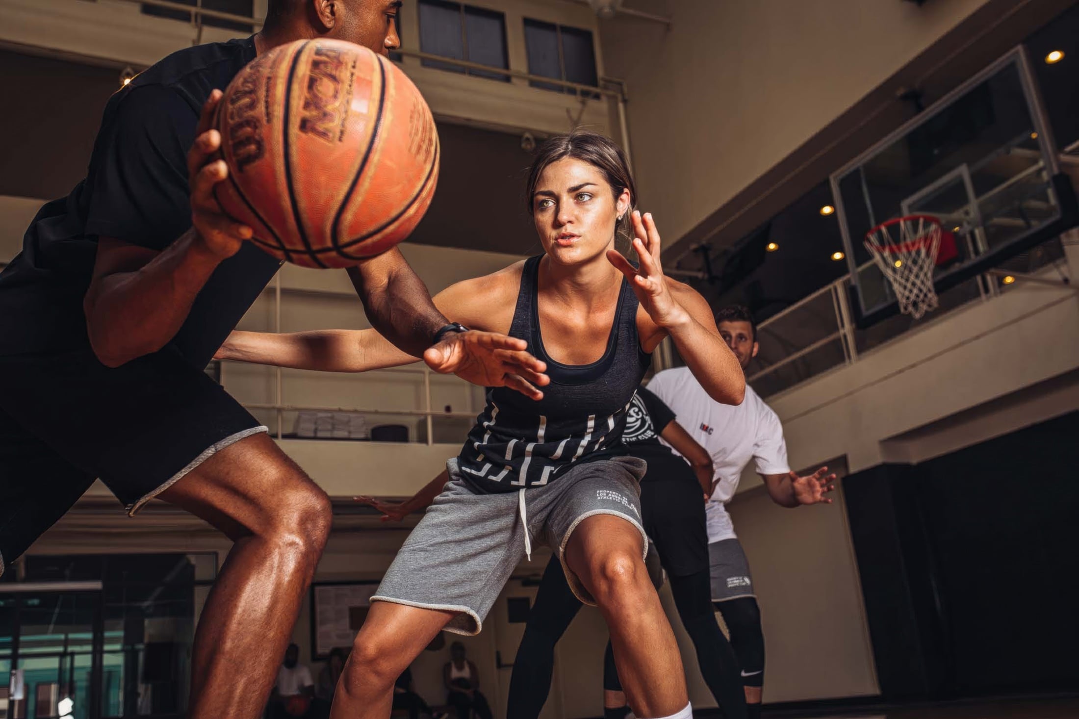 A woman playing defense against a man dribbling a basketball