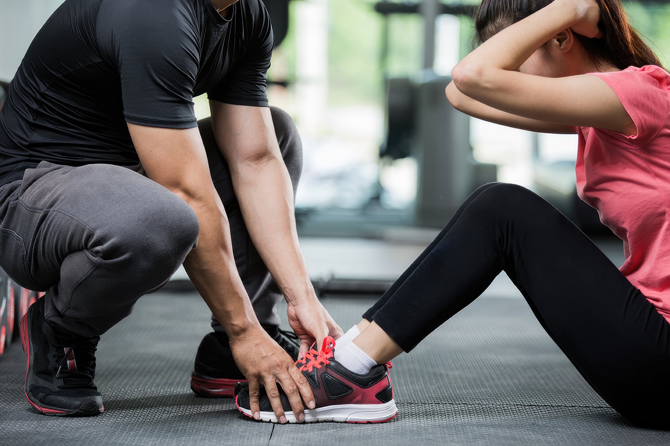 A personal trainer holds their clients feet as they perform sit ups