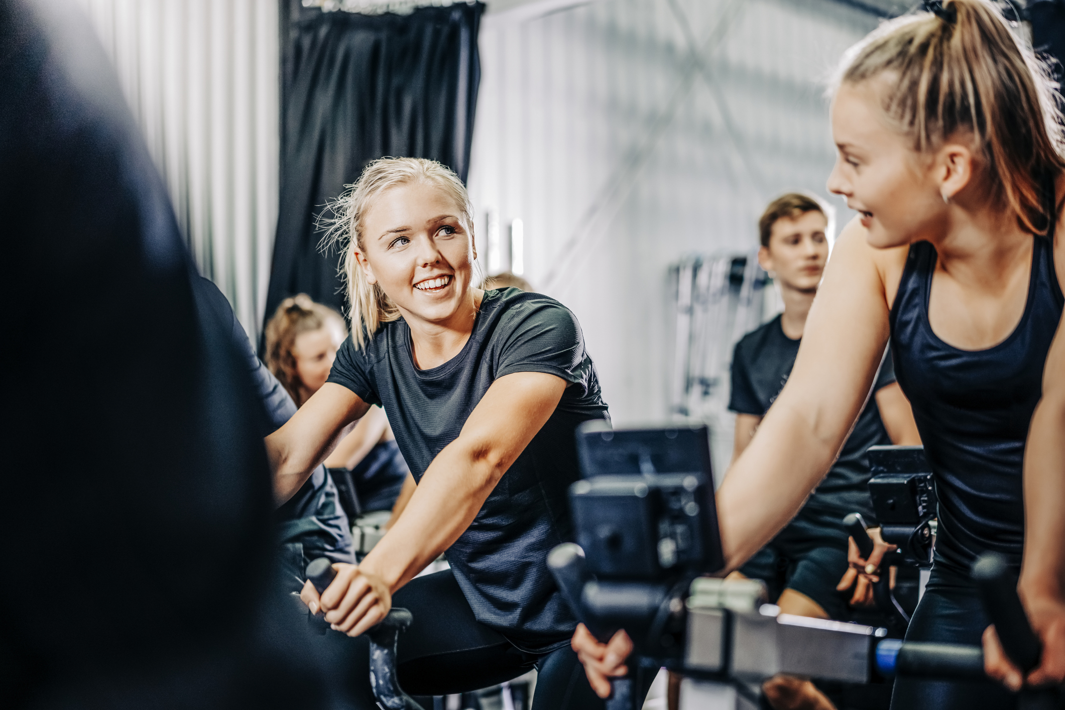 Smiling female athletes cycling in gym