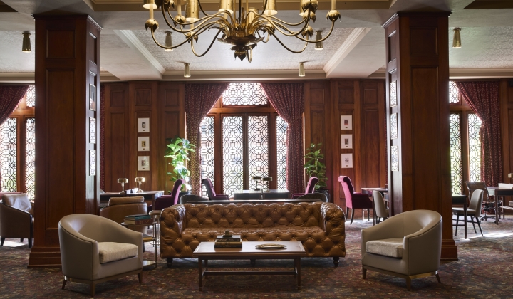 A luxurious lobby with a chandelier, sofa, armchairs, and coffee table.