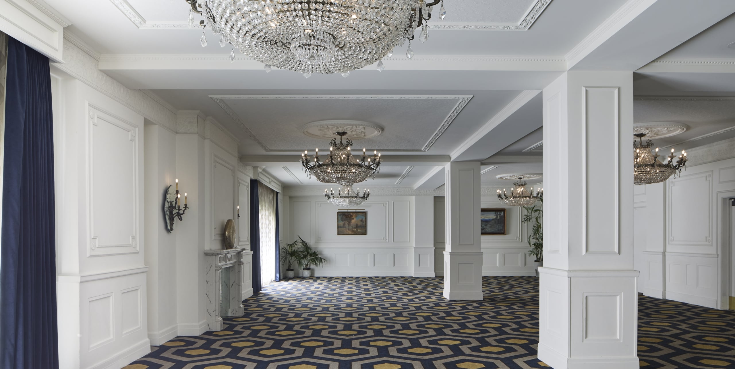A luxurious lobby with a chandelier, columns, and patterned carpet.