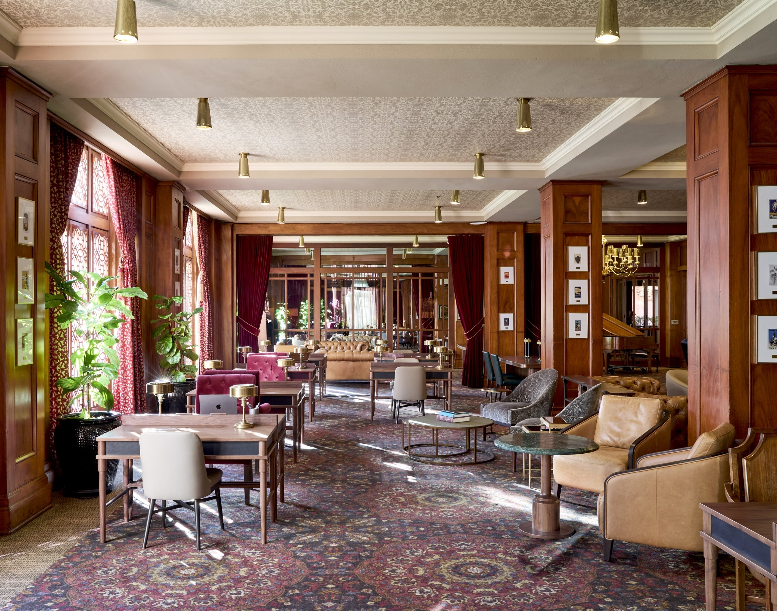 The spacious Olympic lounge with wood paneling, patterned carpet, mixed seating, burgundy drapes, and brass ceiling fixtures.