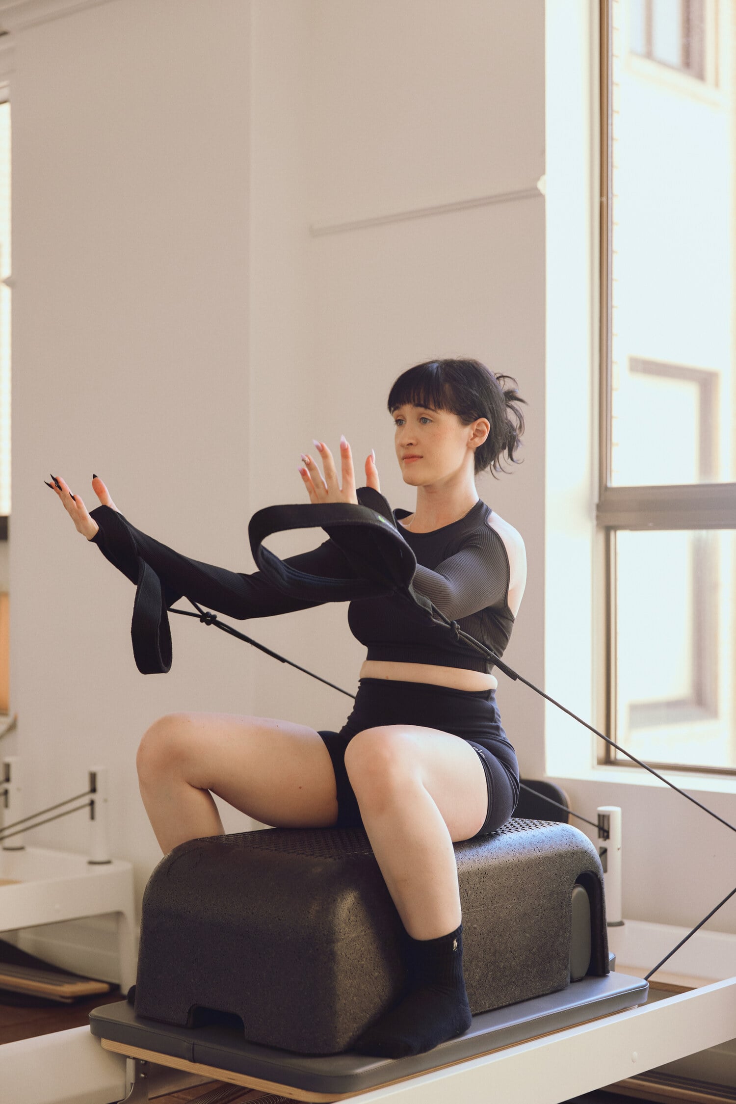 A woman doing arm exercises on a pilates reformer